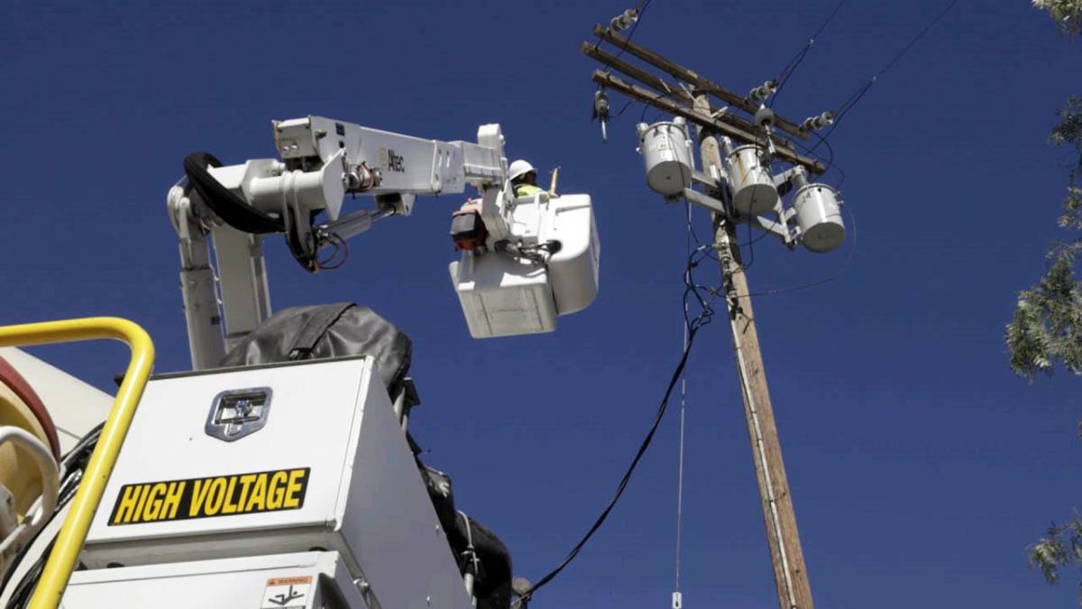 SCE troubleman Paul Chhay is lifted by a bucket truck to complete a repair job.