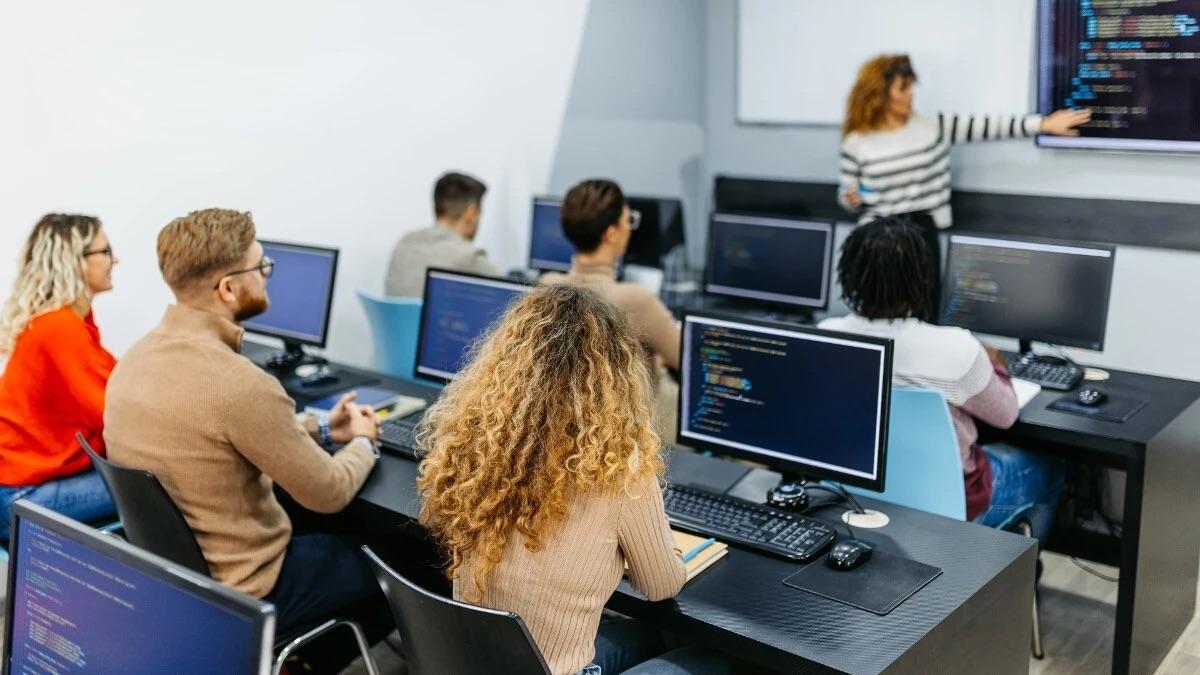 adult students sitting in front of computers in a classroom