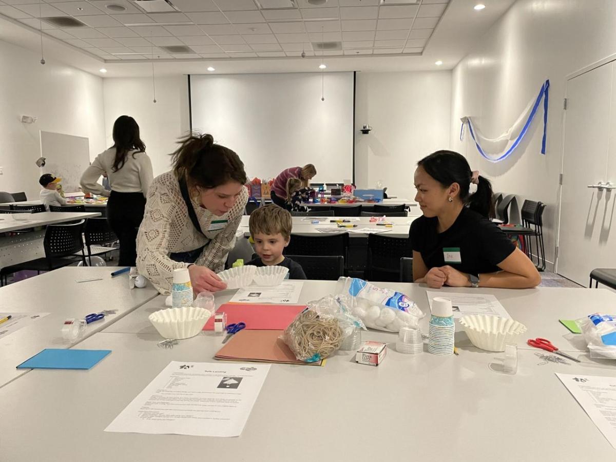 Two adults and a child participating in science experiments and activities