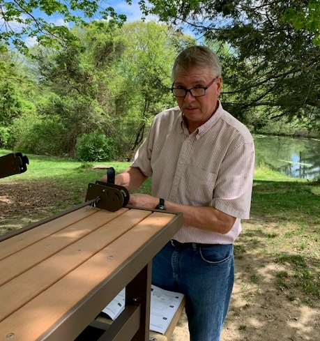 Person stood at the end of a bench outside 