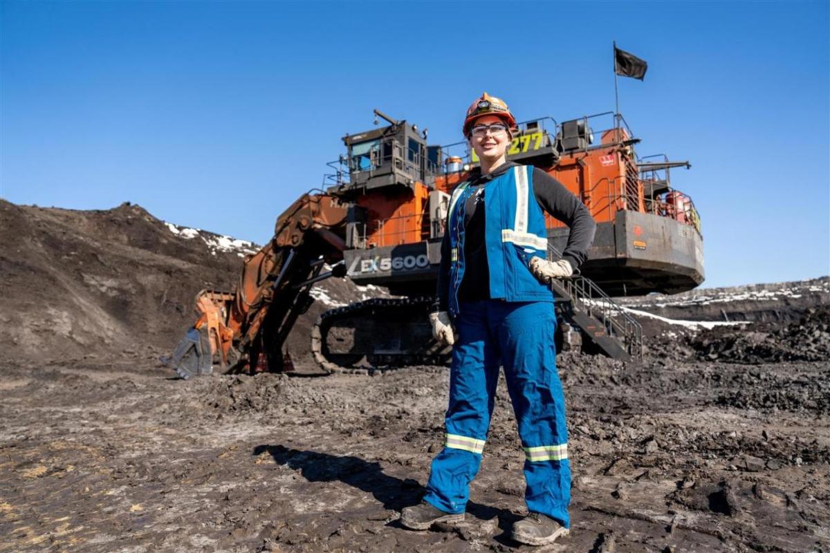 Jenna Plamondon in front of hydraulic shovel