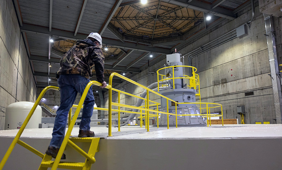 a worker climbing stairs that lead to a walkway over a large turbine