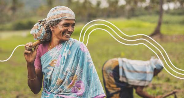 Two people working a field, on standing and smiling.