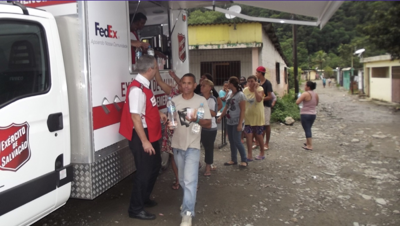 a line of people near a van handing out food and water