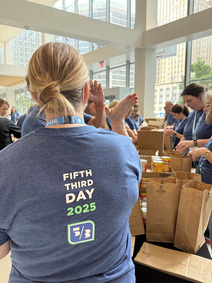 People packing paper bags in "Fifth Third Day 2025" T-shirts