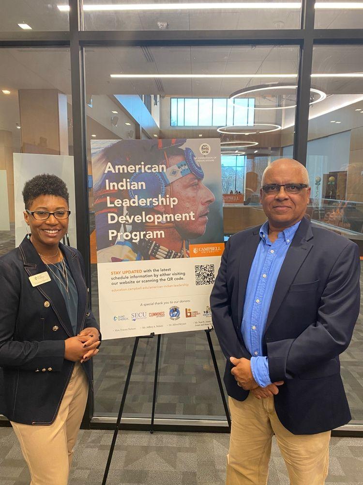 Two people stand beside a poster "American Indian Leadership Development Program."