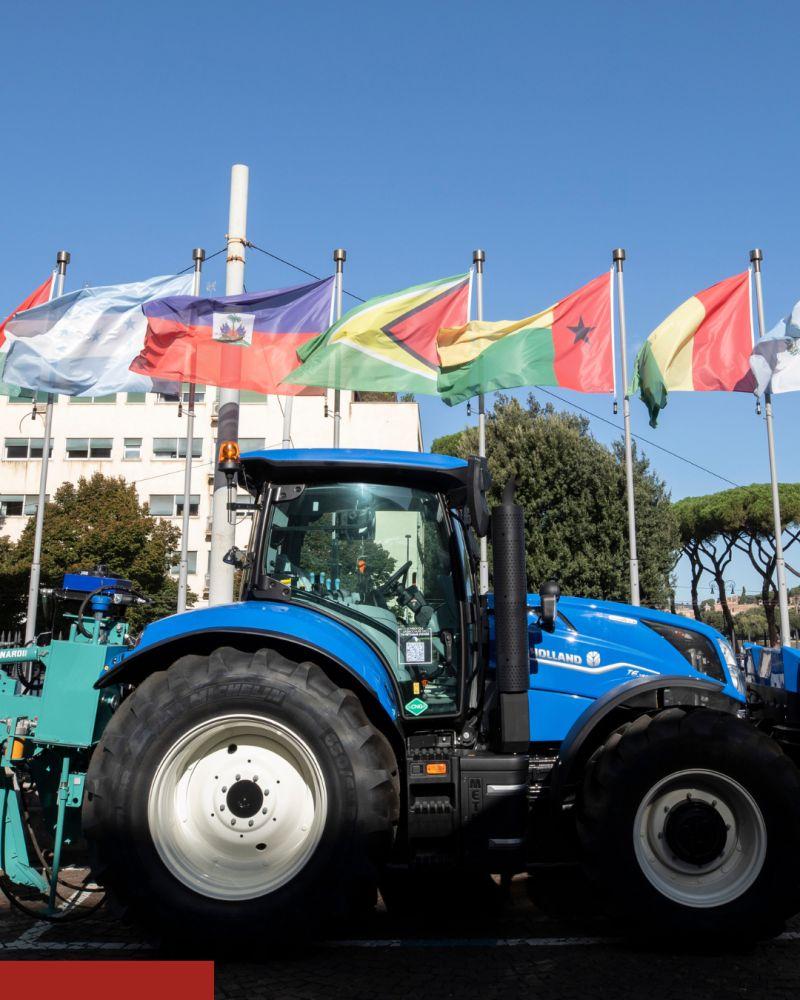 Blue tractor parked outside in front of different flags
