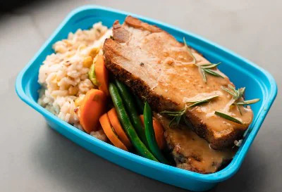 a blue take out container with rice, veggies, protein