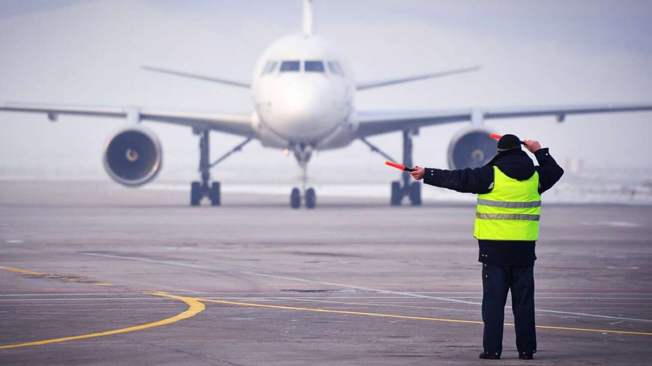a ground crew worker directs an incoming airplane