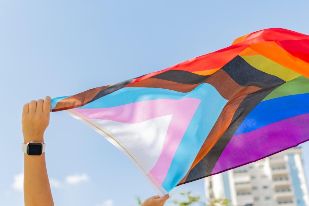 Pride Flag being held up and in the wind.