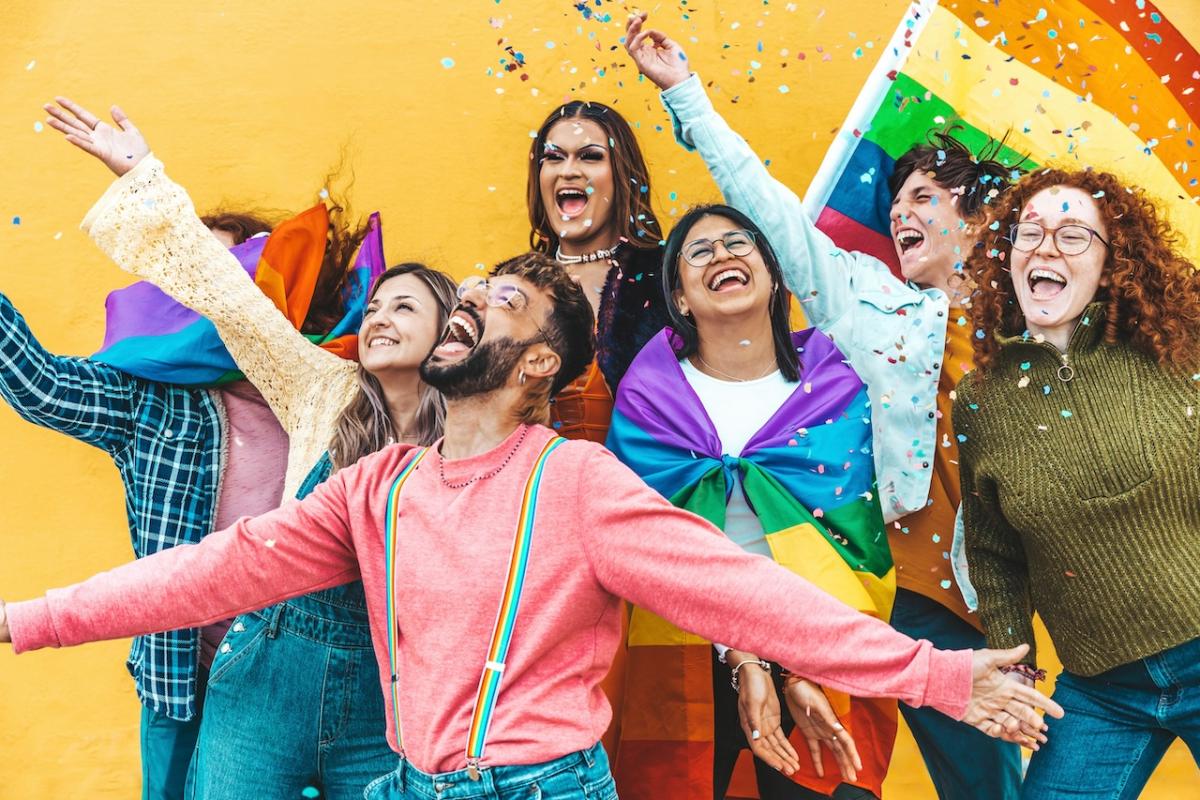 Group of people with a rainbow flag in the background.