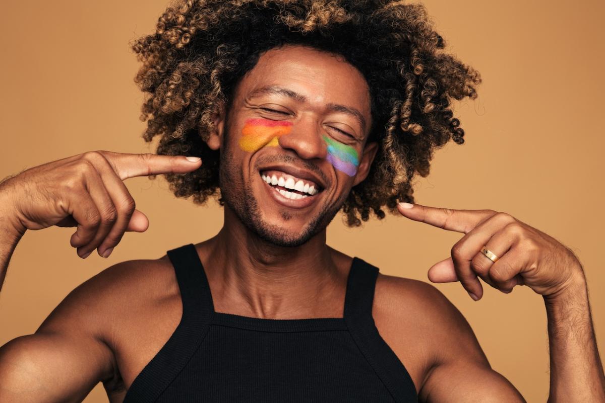 Young person with rainbow make-up on their cheeks.