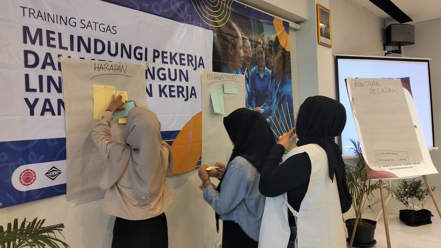 Participants at a training session add notes to large pieces of paper on the wall, documenting their hopes and worries — gender justice agreement