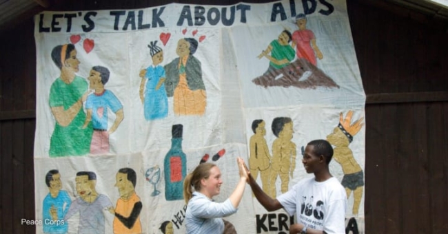 A Peace Corps Volunteer in Kenya gives a high-five to her counterpart while working on HIV/AIDS education. Photo by: Peace Corps