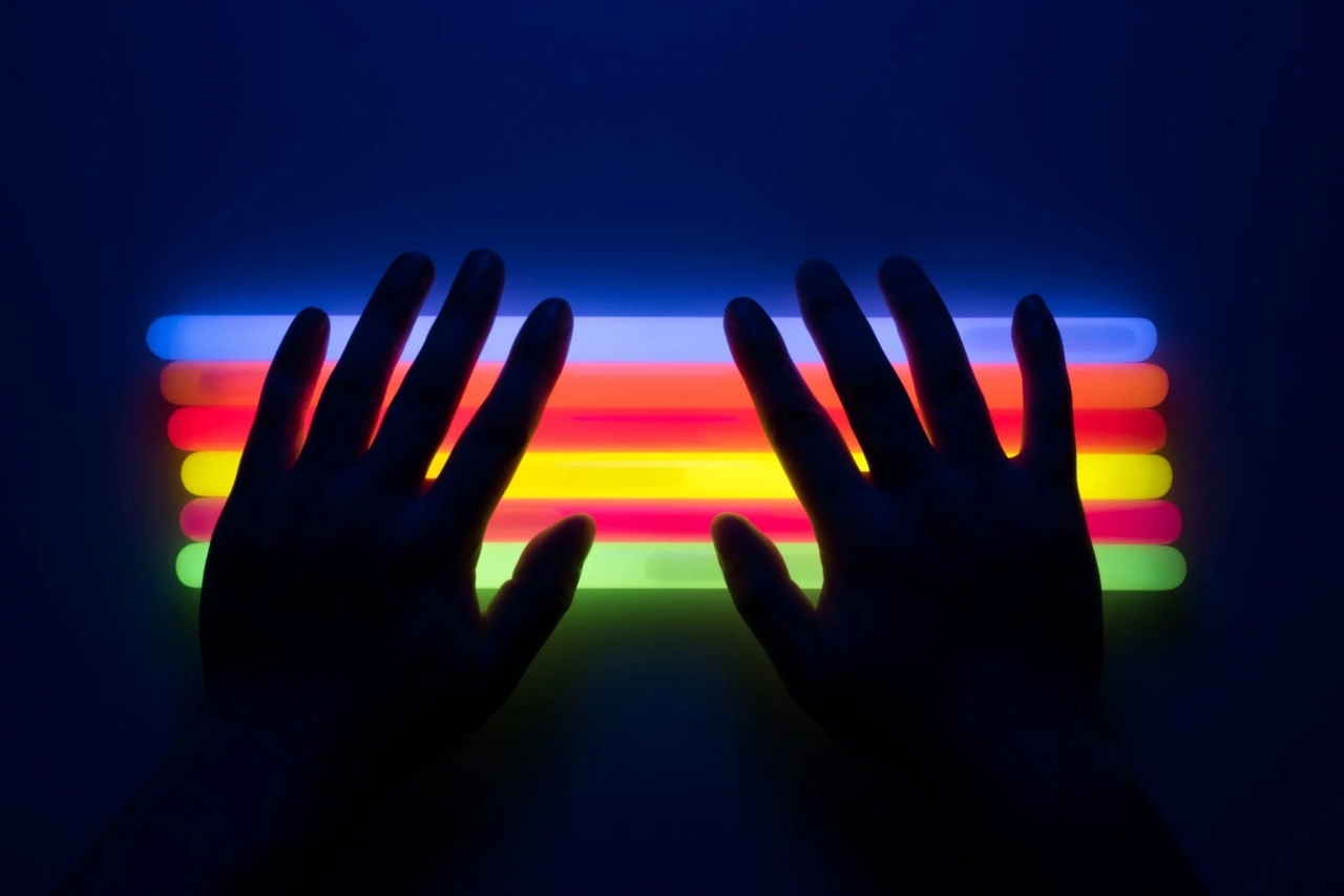 two hands back-lit by a rainbow of colors