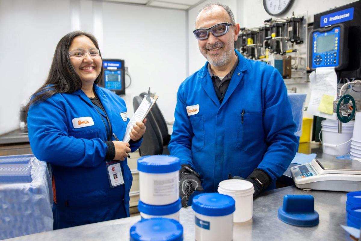 Two people in blue coats smiling in a lab