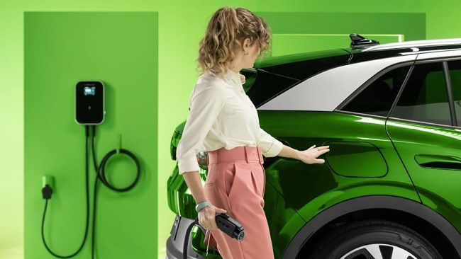 Person plugging in a green electric vehicle