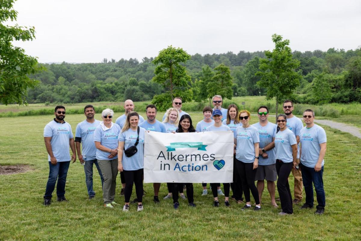 A group of volunteers posed with a sign "Alkermes in Action".