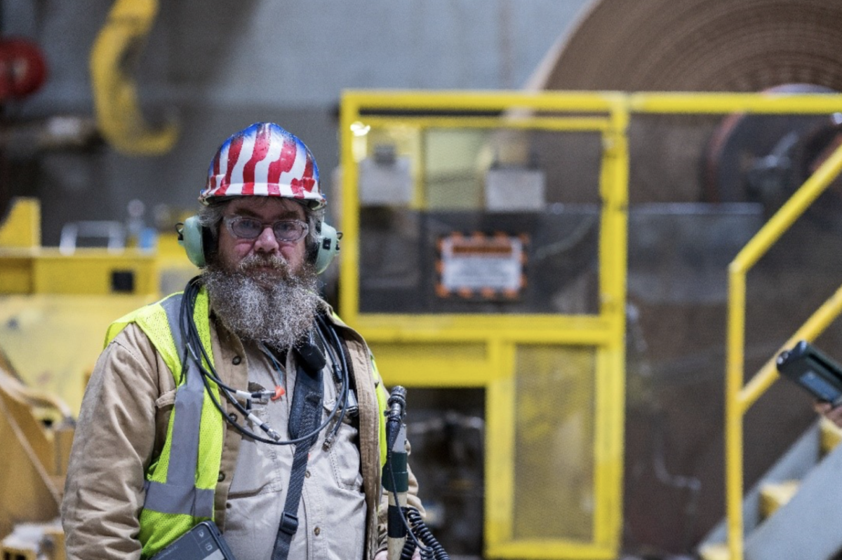 worker with a large beard in safety gear with an American Flag design on his helmet