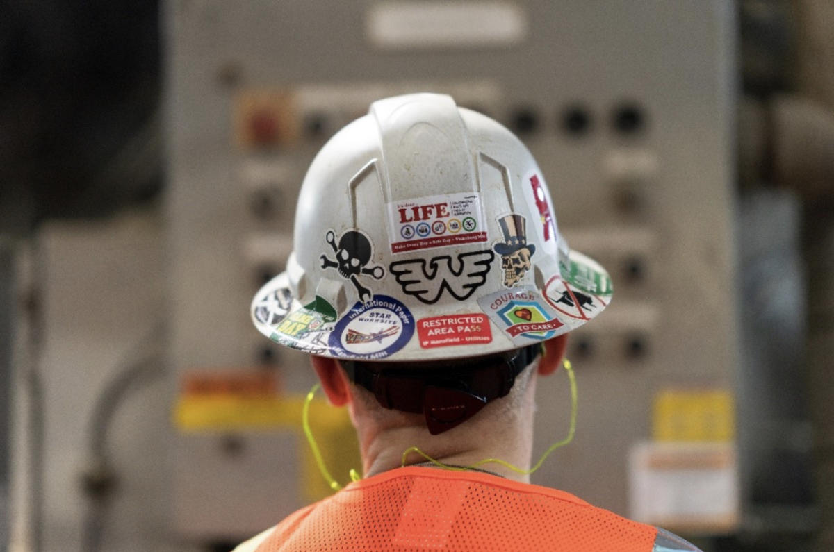 the back of a worker's hard hat covered in stickers
