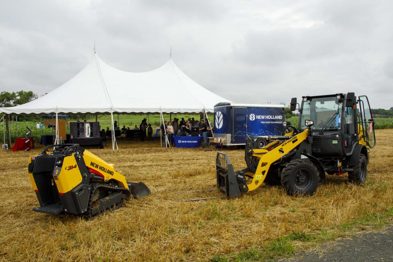 two yellow tractors outside with a tent in the background