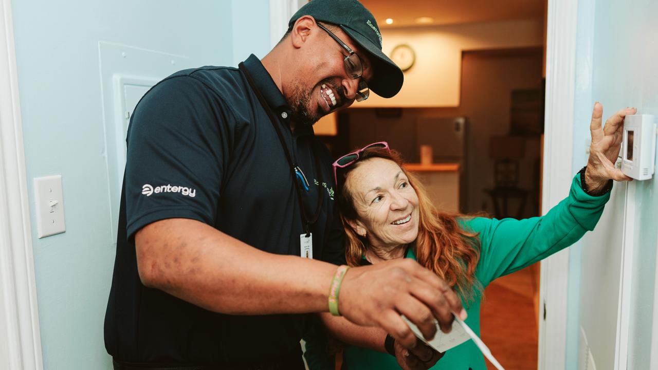 An Entergy employee helping a customer adjust a thermostat