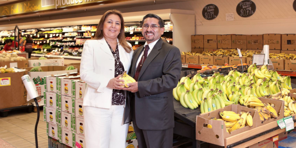 two people standing in the grocery store holding plantains