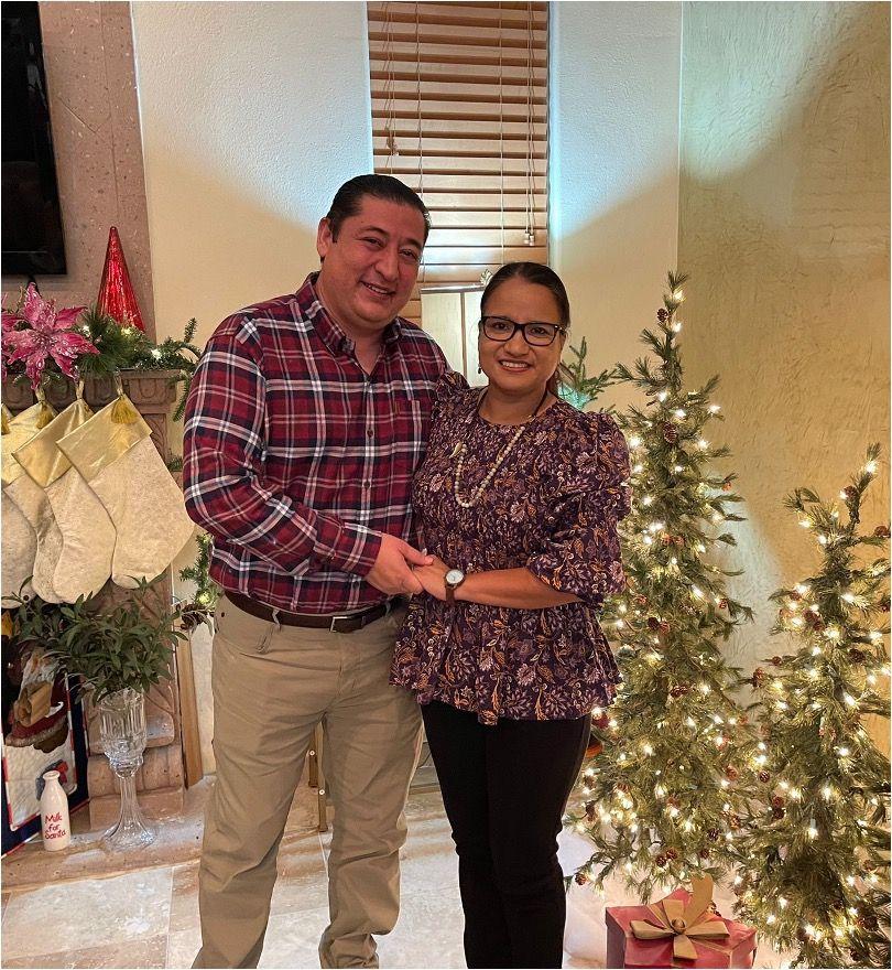 Martin and a woman holding hands in front of Christmas decorations
