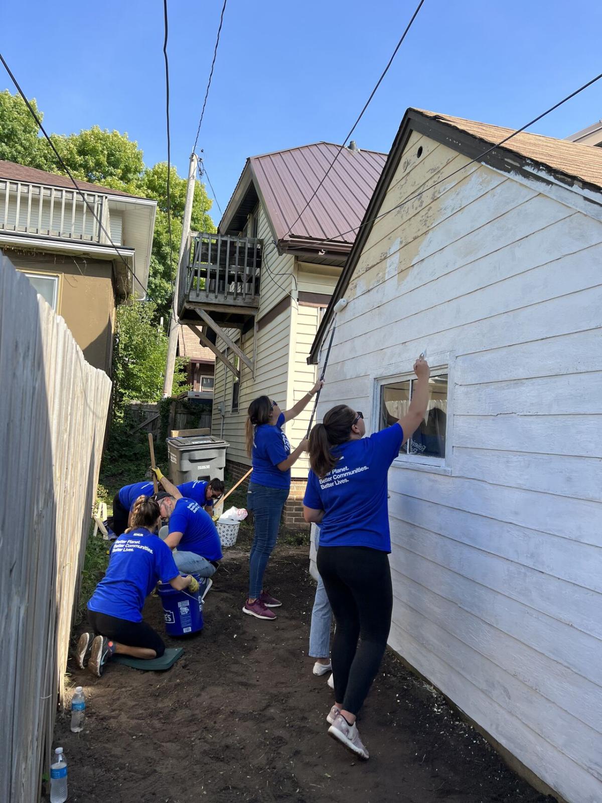 volunteers painting the side of a garage