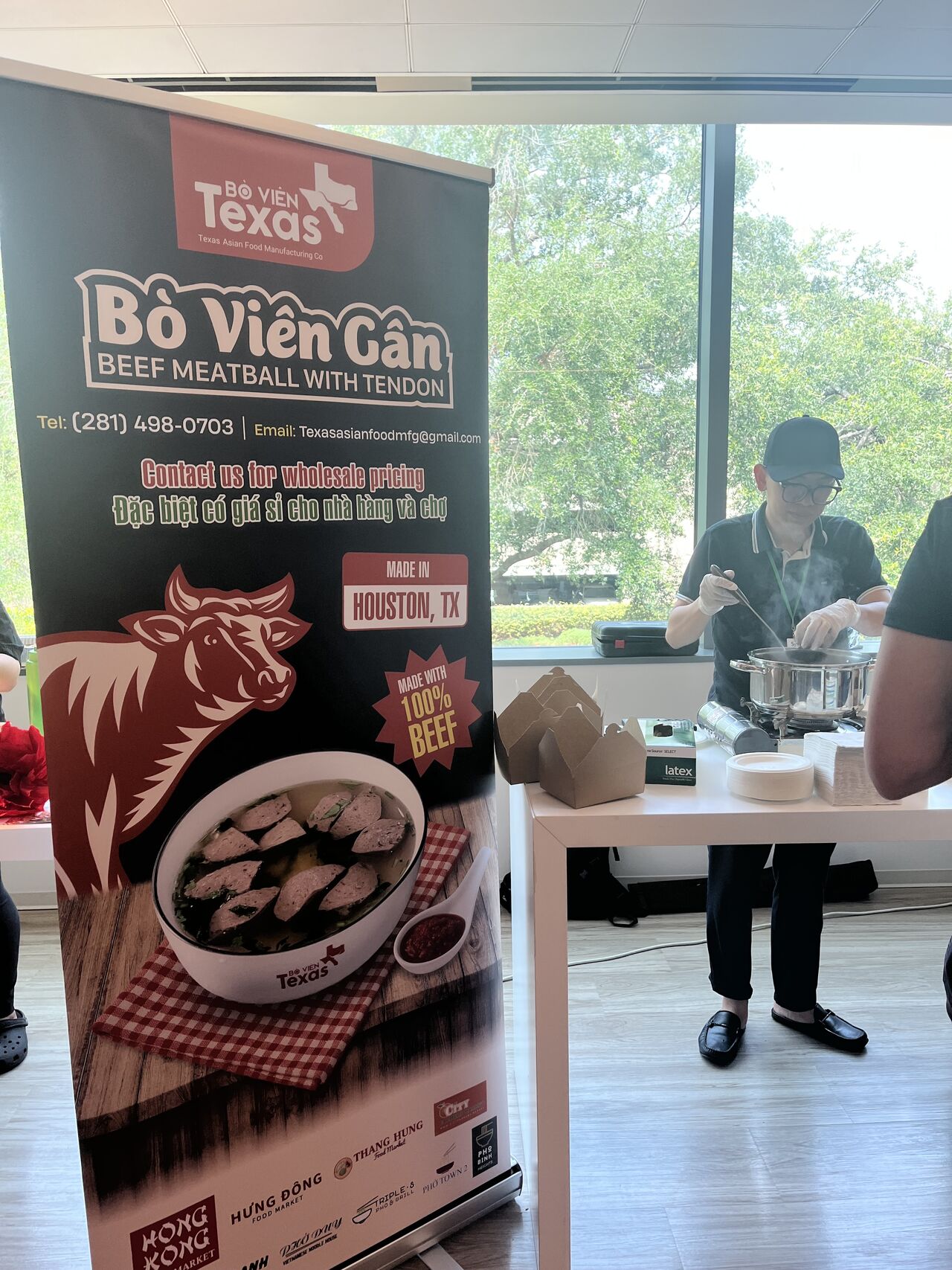 A sign for food in the foreground, with someone serving food in the background