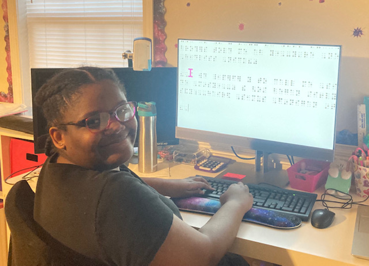 (Amaya, left, a middle school student, is using the laptop, docking station, large screen monitor and external keyboard donated by HP to do a Braille lesson.)