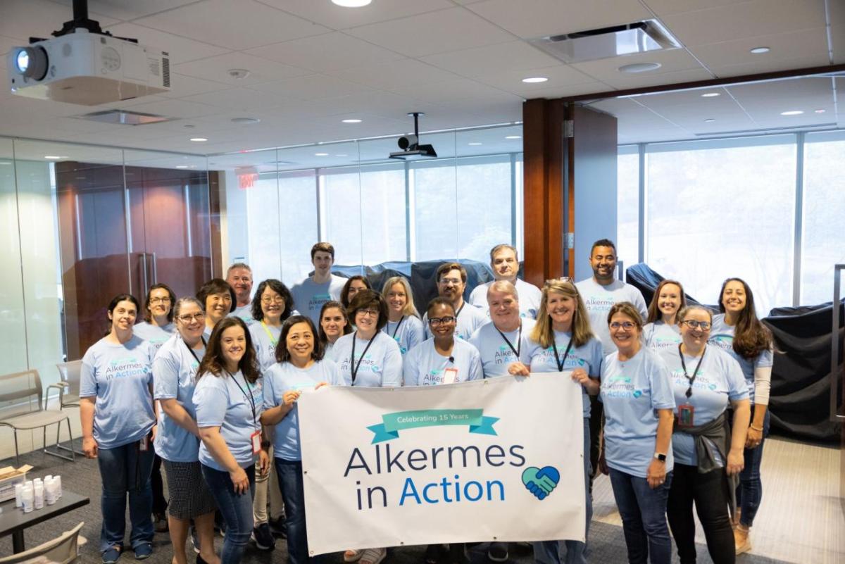 A group of volunteers posed with a sign "Alkermes in Action".