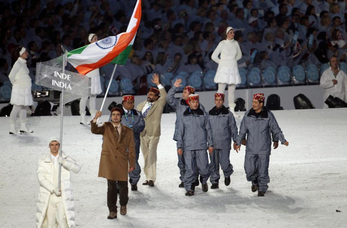 Shiva Keshavan holding the India flag with others in the olympic flag ceremony.