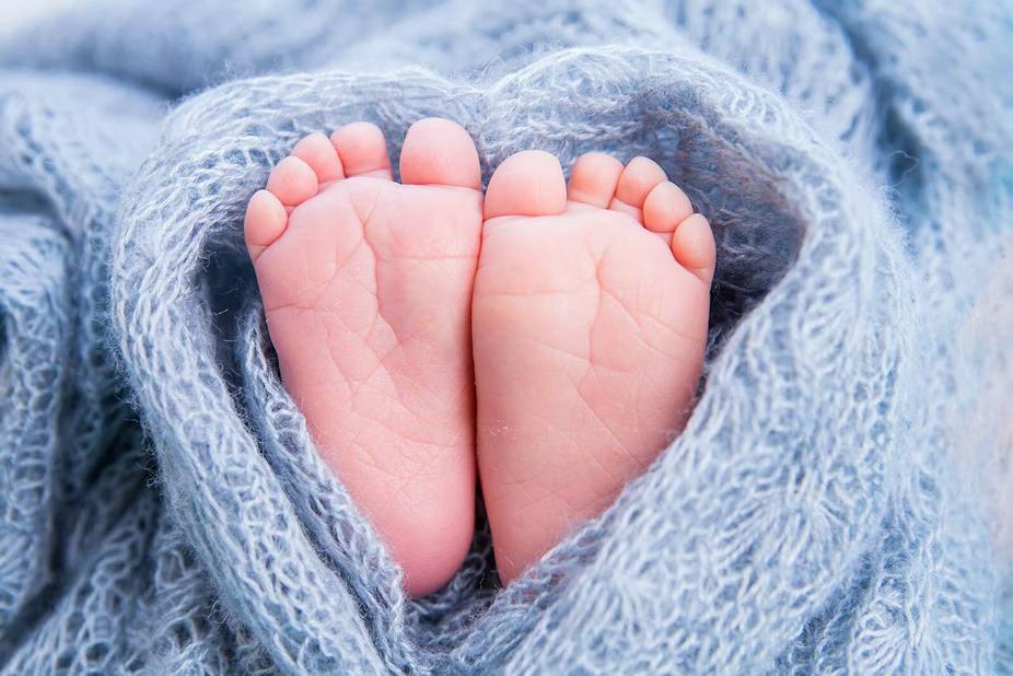 Two baby feet wrapped in a blue blanket.