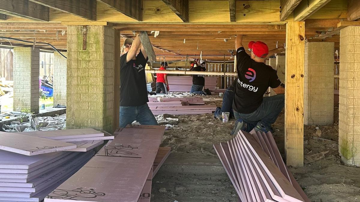 Volunteers installing insulation under a building.
