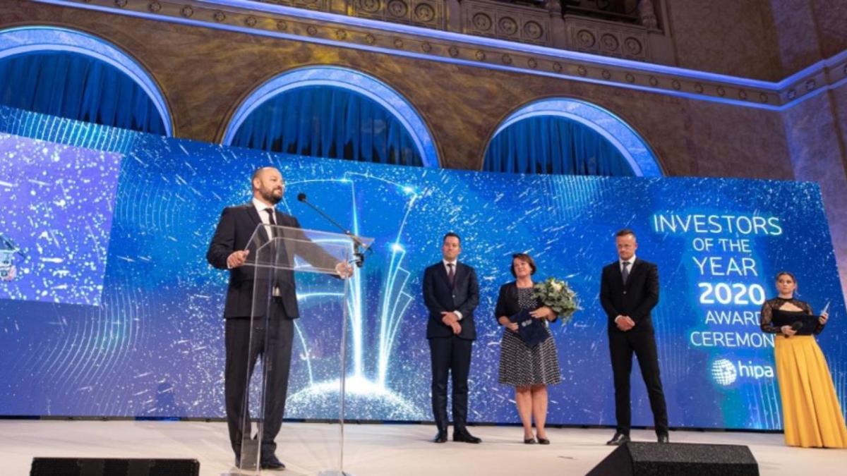 A person at a podium on a stage. Four others behind and to the side.