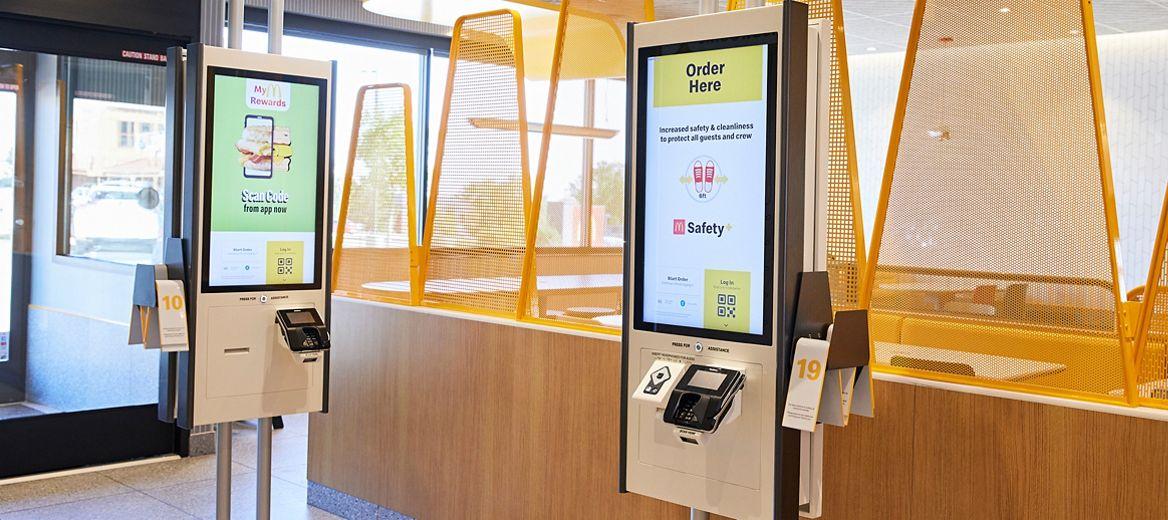 Inside a McDonalds restaurant, two digital kiosks.