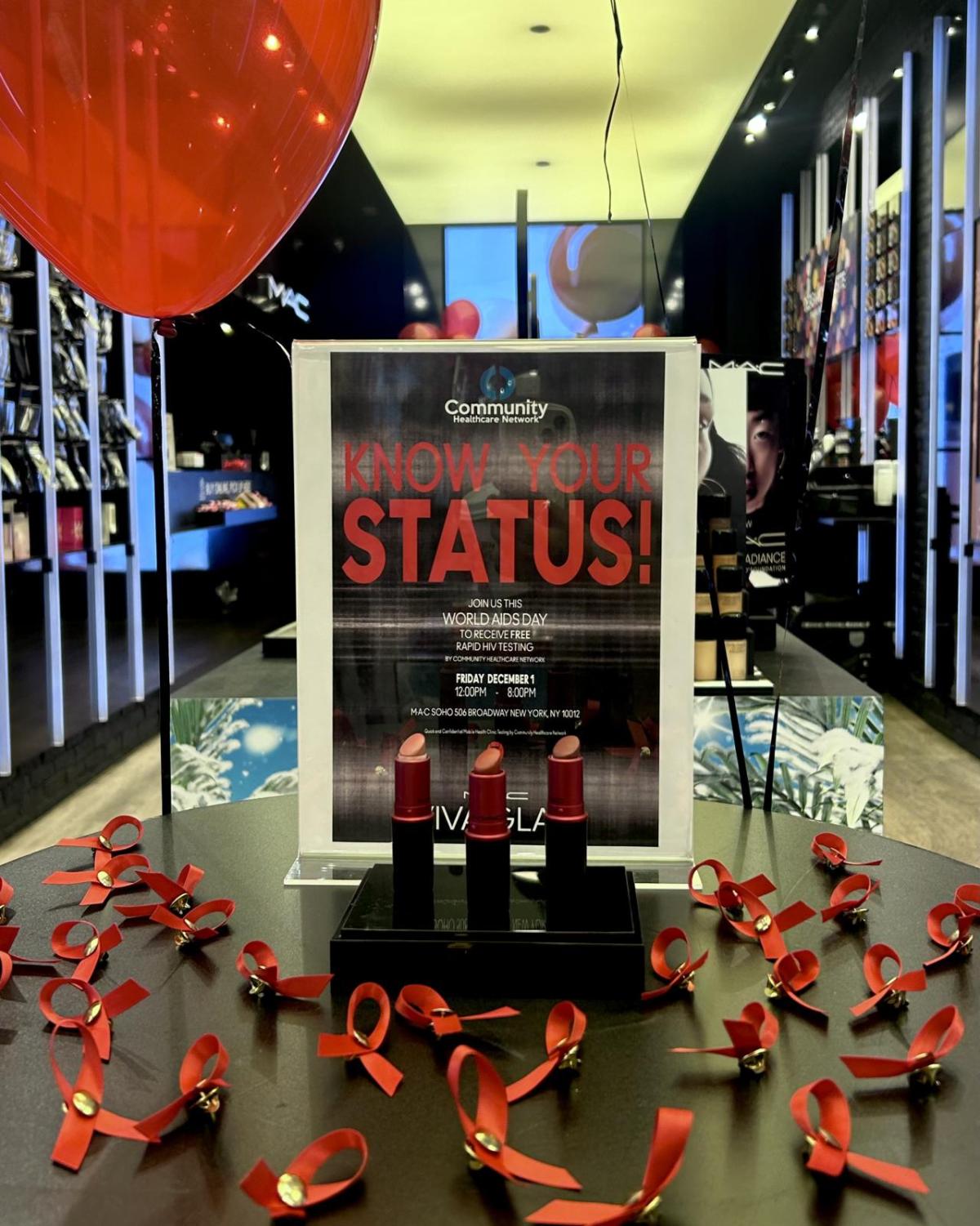 MAC in-store display table with red ribbons and a sign "Know your status".