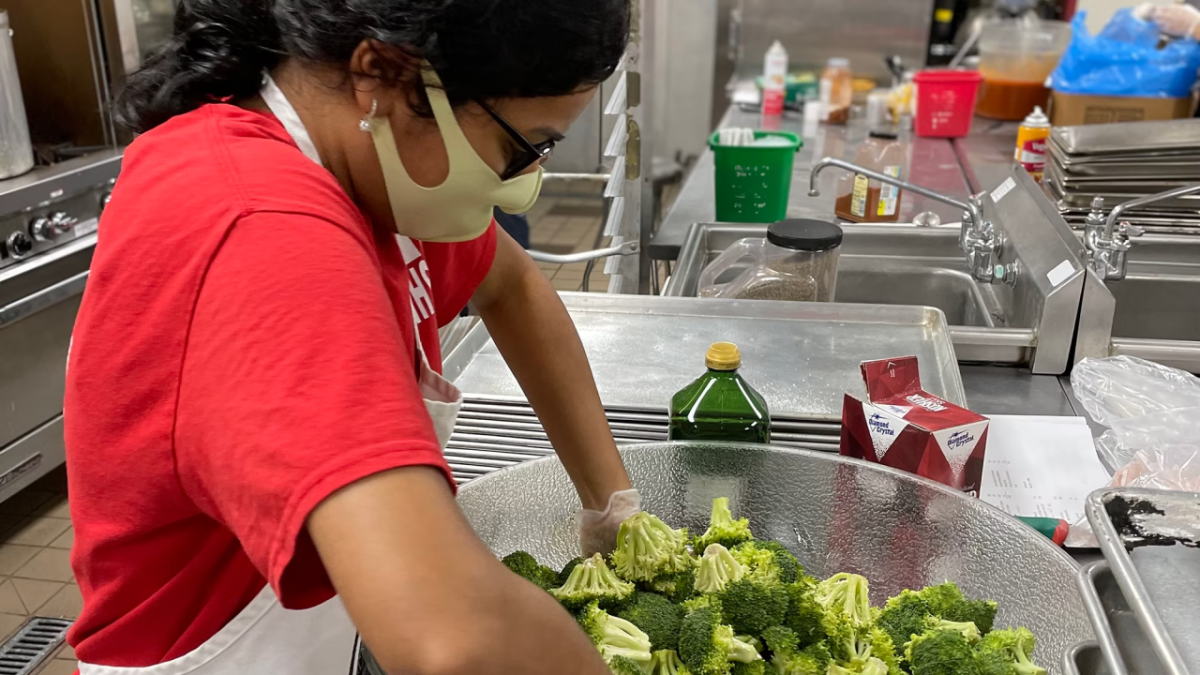 Volunteer mixing broccoli in a bowl
