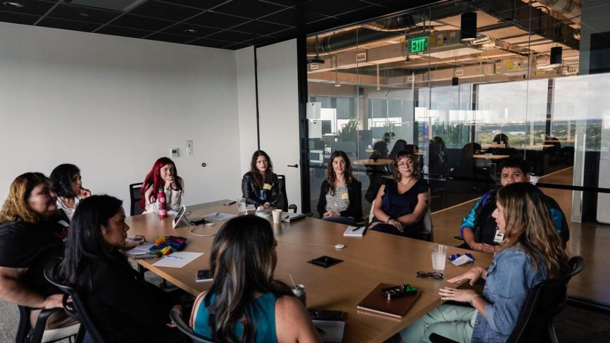 A conference room with a full table of seated people.