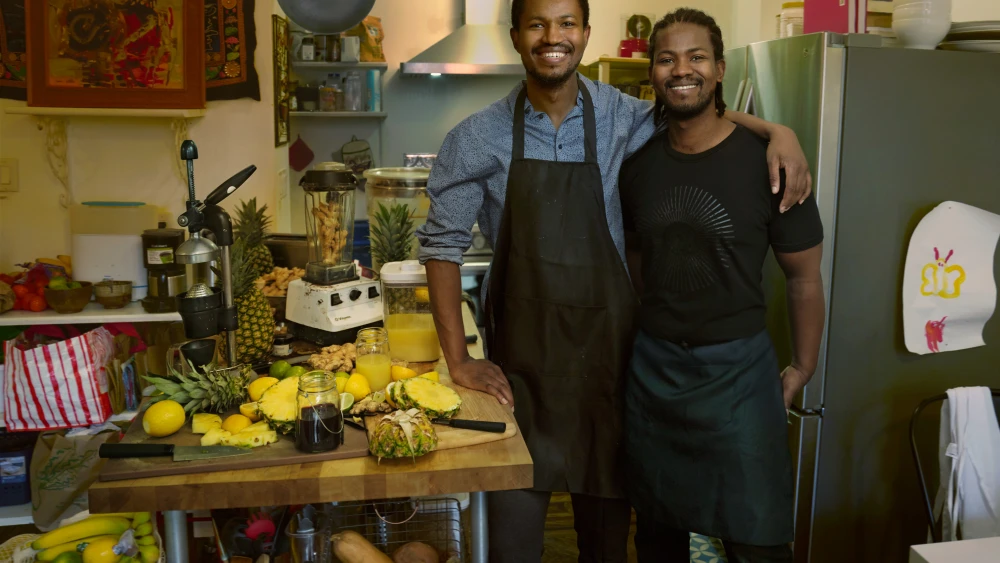 Two men smiling with smoothie making things on a table