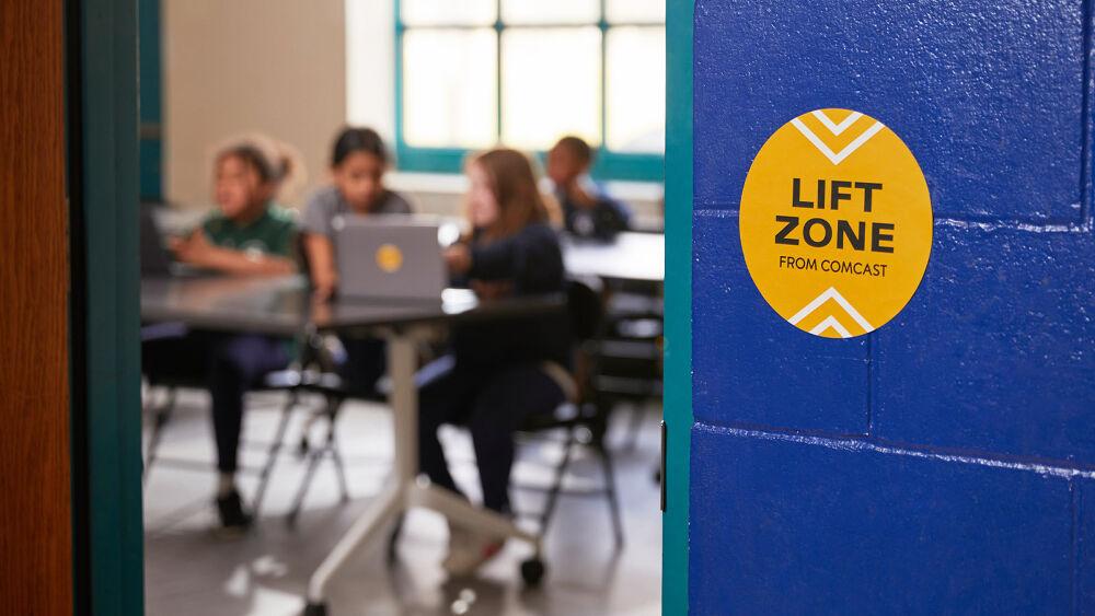 Children in a classroon using laptops. "Lift Zone" sticker on the outside wall of the room.