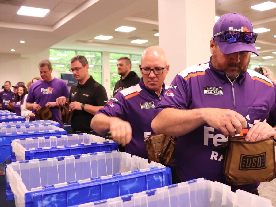 For Frank Hodel (centered), the driver for the FedEx Racing Team Hauler and a U.S. Marine veteran, helps stuff a USO Snack Pack