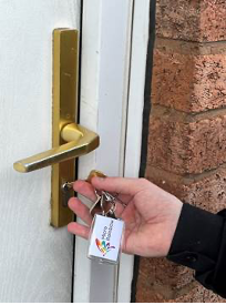 hand holding key with micro rainbow logo in front of an exterior door