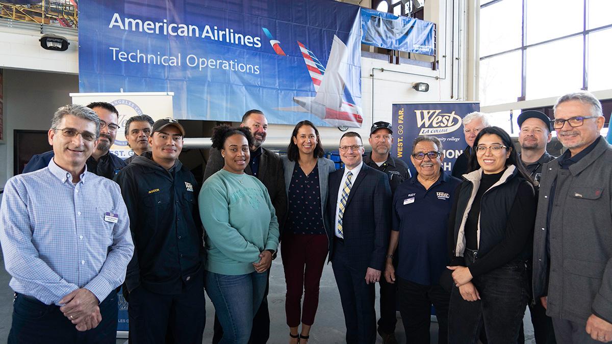 A group of employees and students posed in front of a large banner "American Airlines Technical Operations."