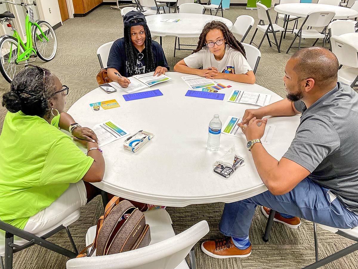 Four people seated at a round table, worksheets in front of them