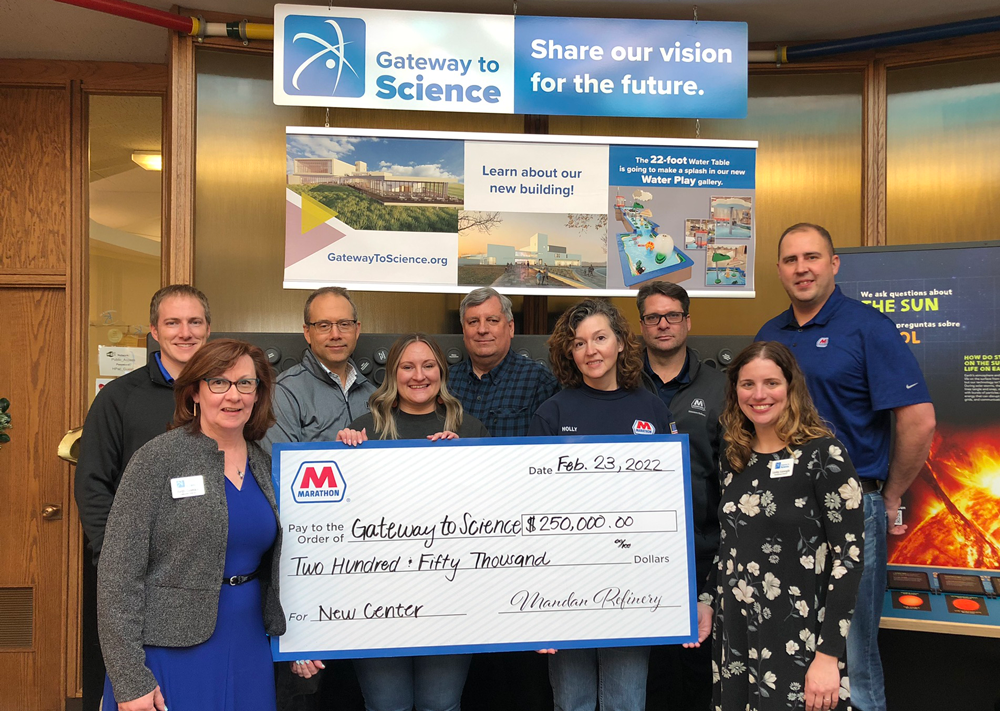Group of 9 people stand in front of a "gateway o science" display holding a large check from Marathon petroleum 