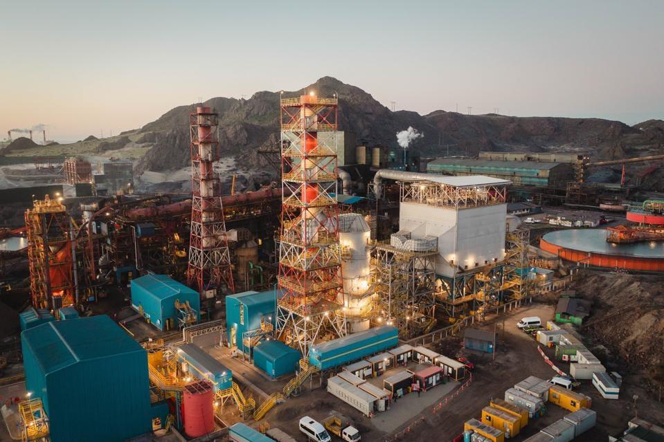 aerial view of a large industrial complex, a mountain range in the background.