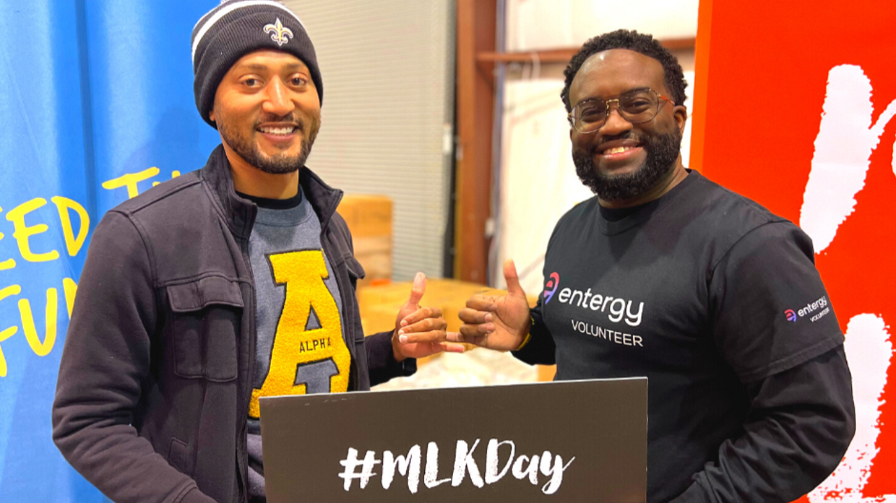 Two people holding a sign "MLKDay" and giving thumbs-up.