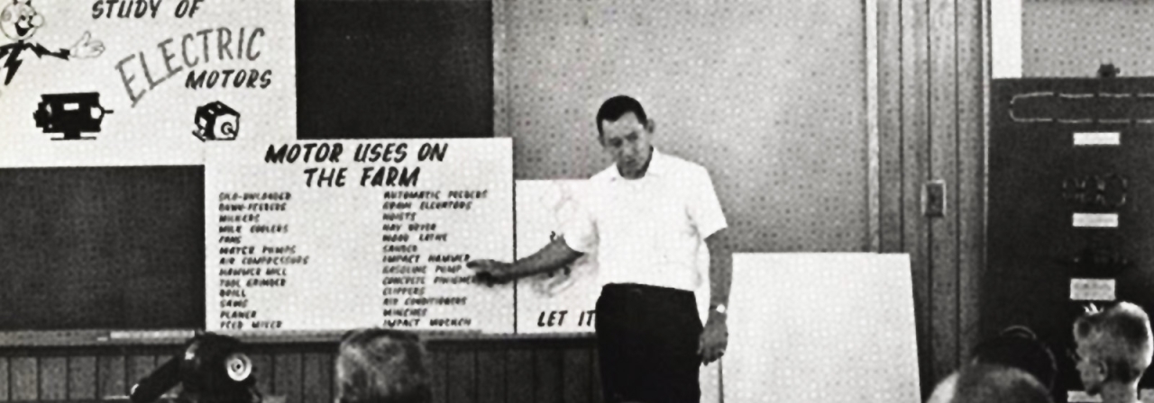 An old photo, a representative from Duke Power giving a presentation to a group of children about motor uses on the farm